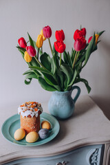 a bouquet of tulips and an Easter cake with colored eggs 