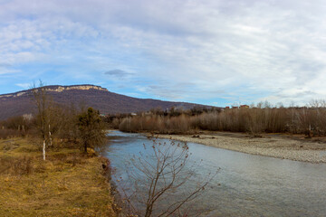 Autumn, shallow mountain river, calm flow on the plain clear water.