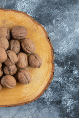 A wooden board of healthy walnuts on a gray background
