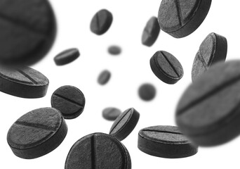 Black activated carbon tablets levitate on a white background
