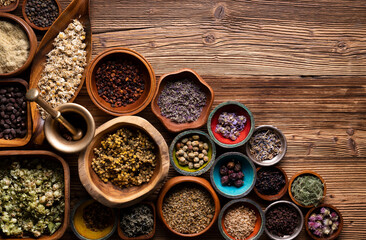 Natural medicine background. Assorted dry herbs in bowls and brass mortar on rustic wooden table.