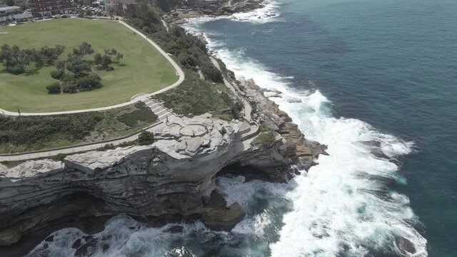 Waves Crashing Against Rocky Inlet And Cliffs Of Mackenzies Point Peninsula In Tamarama, NSW, Australia. - aerial