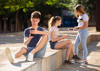 Portrait of teenager carried away with smartphone outdoor on summer day..
