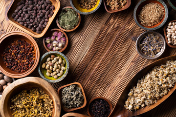 Natural medicine background. Assorted dry herbs in bowls and brass mortar on rustic wooden table.