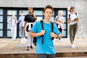 Positive teenager walking in the street, carrying a bag on one shoulder