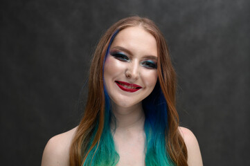 Fototapeta premium portrait of a girl with dyed hair smiling on a gray background