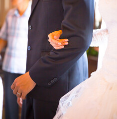 The bride holds the groom's arm at a Christian wedding in the chapel.
