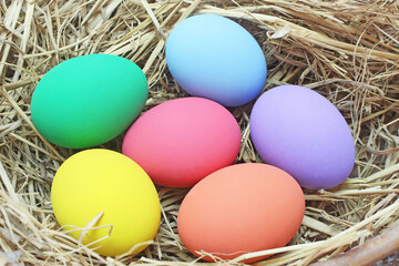 straw basket with easter eggs on wooden background