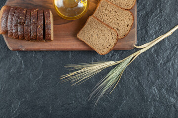 Fototapeta na wymiar Slices of brown bread with wheat on a wooden board