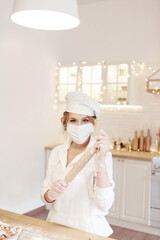 baking by the chef in the medical mask. A woman in a white hat with a rolling pin in the kitchen