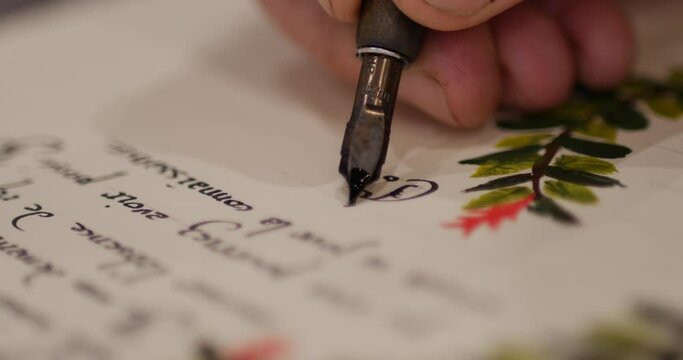 Man writing a embellished letter with calligraphy gothic letters. Man writing an old letter. Old quill pen, books and papyrus scroll on the table. Historical atmosphere. writing a document on a sheet