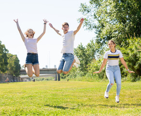 Obraz premium Happy teenagers jumping on the green lawn on spring