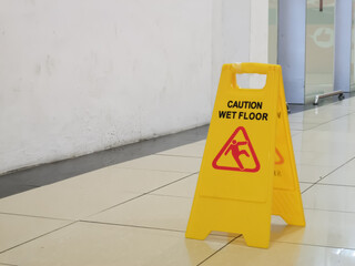 Selective focus image with noise effect shopping mall interior with wet floor caution sign.