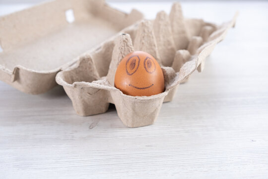 Smiling egg in a cardboard box.