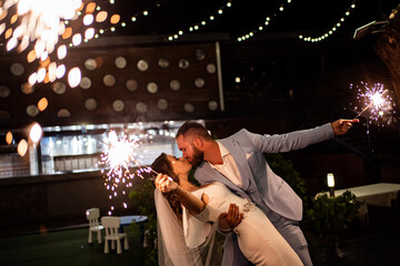 newlyweds with sparklers in night park with garlands in trees. ending to wedding