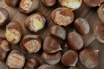 A wooden board with healthy chestnuts on a gray background