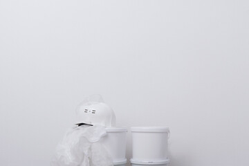 buckets of paint, protective clothing and a hard hat against a white wall, there is a place for writing © kurgu128