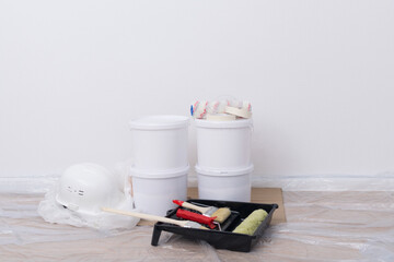 a set of building materials, buckets of paint, protective clothing and a helmet on a white wall background © kurgu128