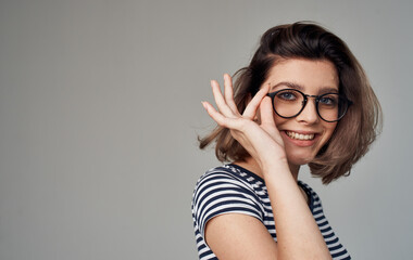 portrait of a happy blonde in a striped t-shirt and his glasses on a gray background