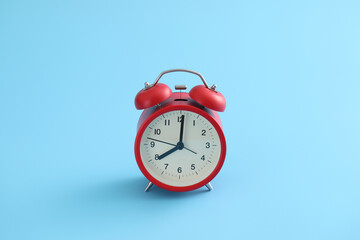 Red retro alarm clock isolated on a blue background