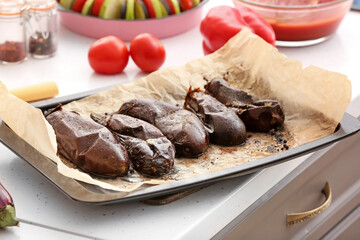 Tray of tasty baked eggplant on table in kitchen, closeup