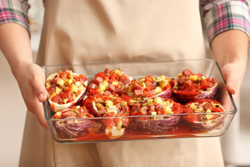 Woman holding baking dish of tasty vegetables, closeup