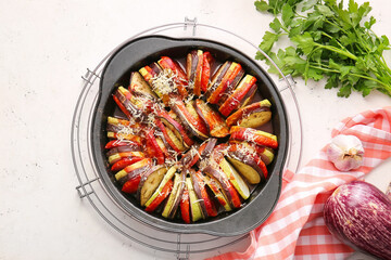 Dish of tasty baked eggplant and tomatoes on light background