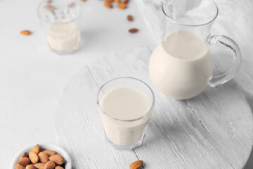 Obraz na płótnie Canvas Jug and glass of tasty almond milk on light background