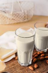 Glasses of tasty almond milk on color background