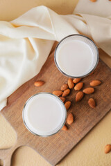 Glasses of tasty almond milk on color background