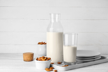 Bottle and glass of tasty almond milk on light background