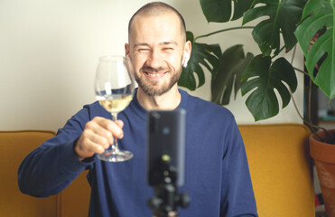 Online party concept. The man with a glass of white wine is video calling by smartphone the girl from his apartment. Online dating, virtual meeting, internet dates. Selective focus