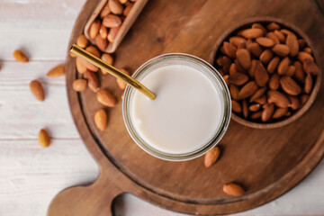 Glass of tasty almond milk on wooden background