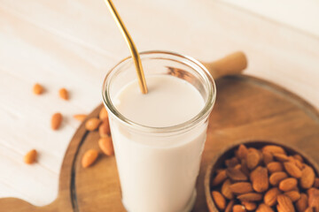 Glass of tasty almond milk on wooden background
