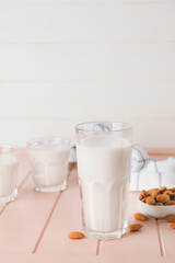 Glasses of tasty almond milk on light wooden table
