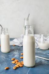 Bottles of tasty almond milk on color table