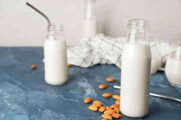 Bottles of tasty almond milk on color table
