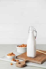 Bottle of tasty almond milk on color wooden table