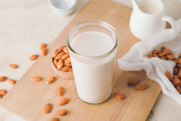Glass of tasty almond milk on light background