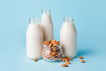 Bottles of tasty almond milk on color background