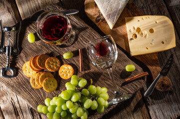 Fototapeta na wymiar Tasting cheese platter with grapes and fruits on an old wooden table. Food for wine and romantic, cheese delicacies. Menu design horizontally. View from above.