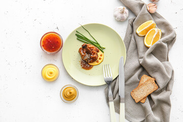 Plate with tasty chicken lollipop on light background