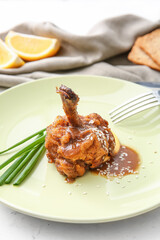 Plate with tasty chicken lollipop on light background
