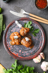 Plate with tasty chicken lollipops on dark background