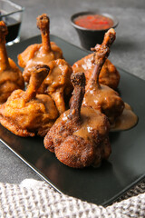 Plate with tasty chicken lollipops on dark background