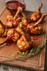 Board with tasty chicken lollipops on wooden background