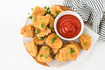 Homemade chicken nuggets with ketchup on a wooden board