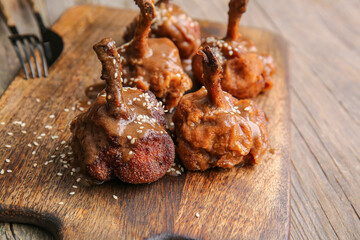 Board with tasty chicken lollipops on wooden background