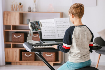Little boy studying music with his friend online at home