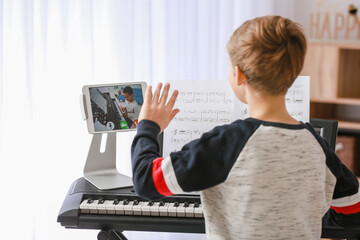 Little boy studying music with his friend online at home